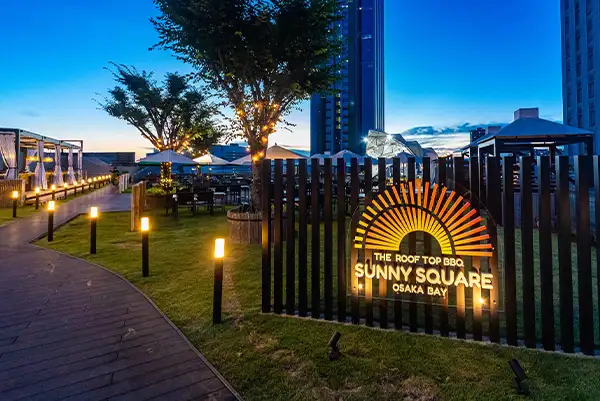 「THE ROOF TOP BBQ SUNNY SQUARE OSAKA BAY」ザ・ルーフトップ バーベキュー サニースクエア 大阪ベイの入り口看板をライトアップ